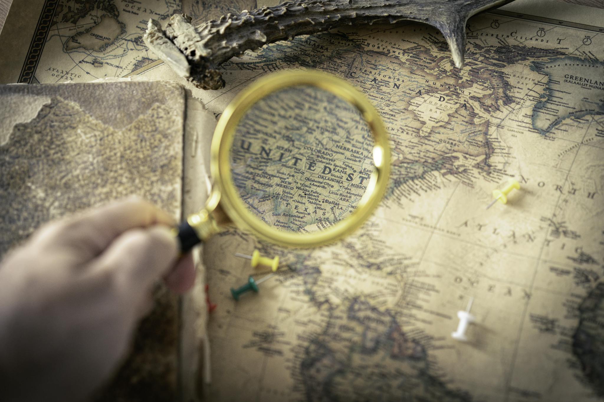 Hand holding magnifying glass over vintage USA map, capturing exploration and discovery theme.